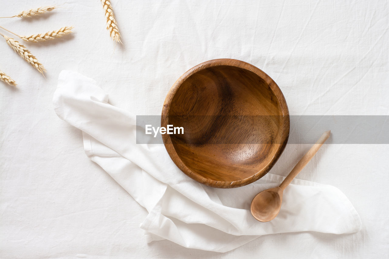 Empty wooden bowl, spoon and ear on cloth. top view. eco-friendly concept