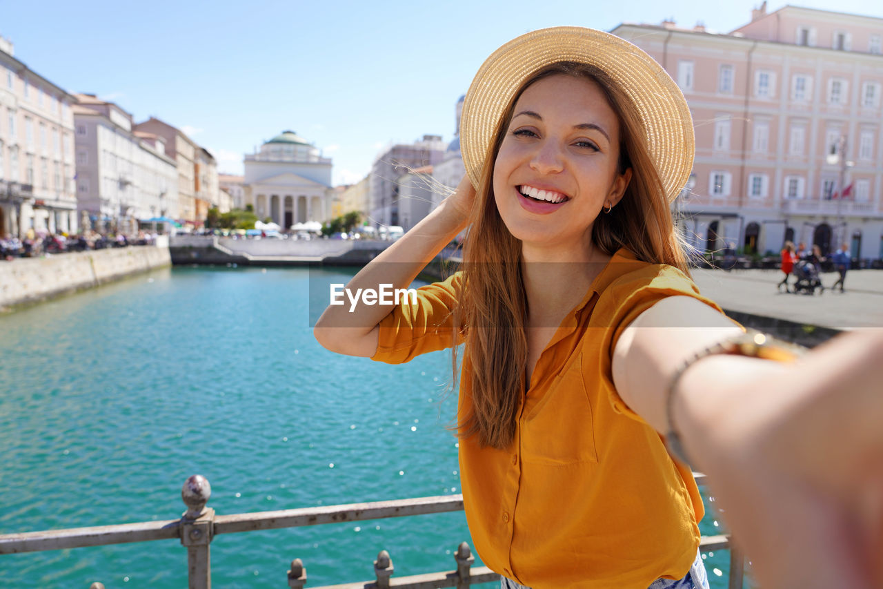 Woman making selfie photo standing on the bridge with beautiful view on trieste city in italy