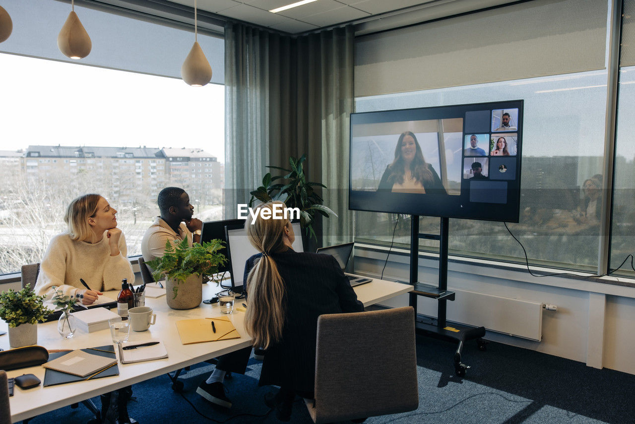 Businesswoman doing video call with male and female colleagues in conference room at office