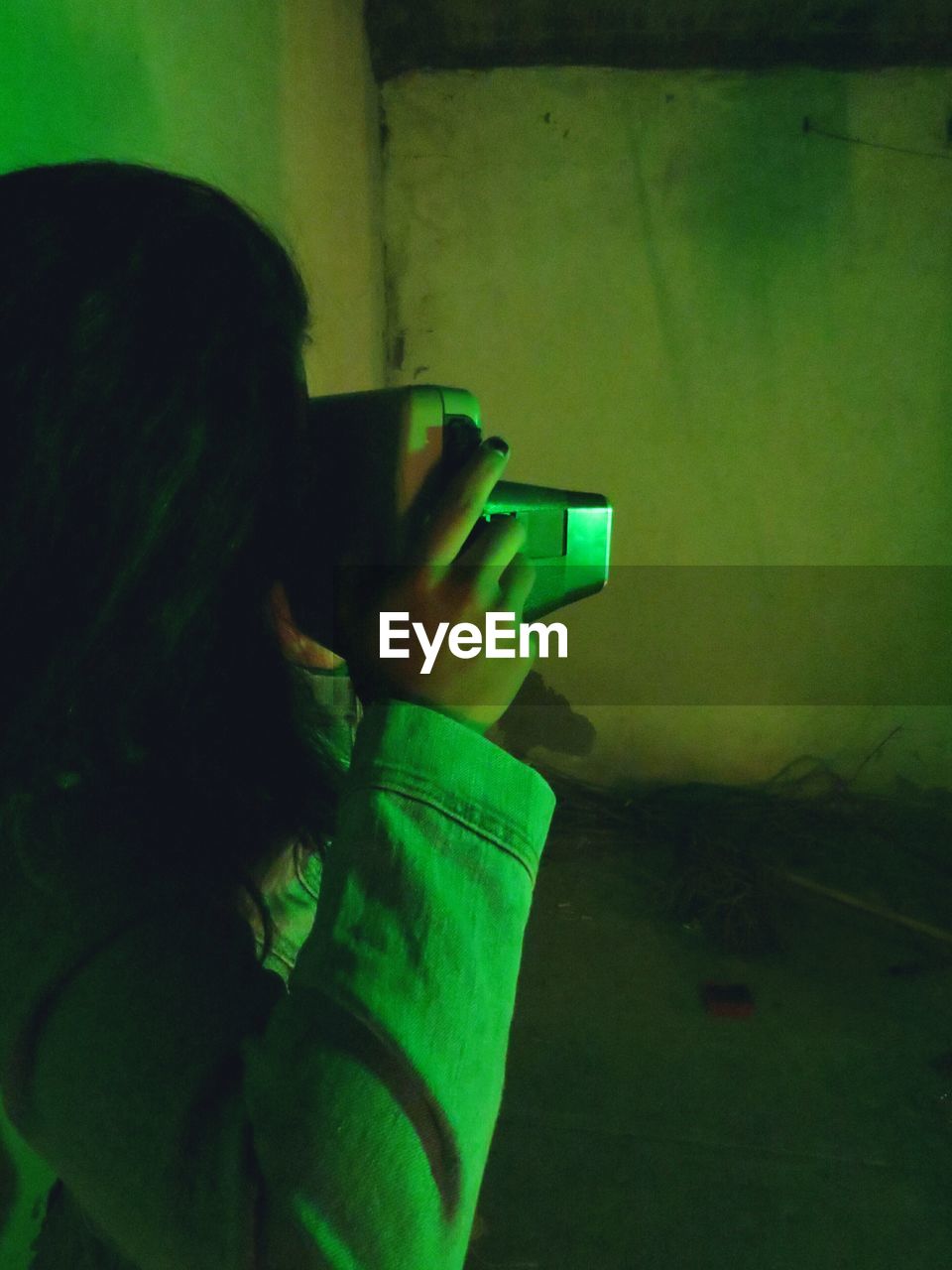 Woman photographing against wall at night