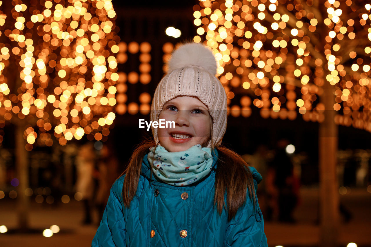 portrait of smiling young woman standing in city at night