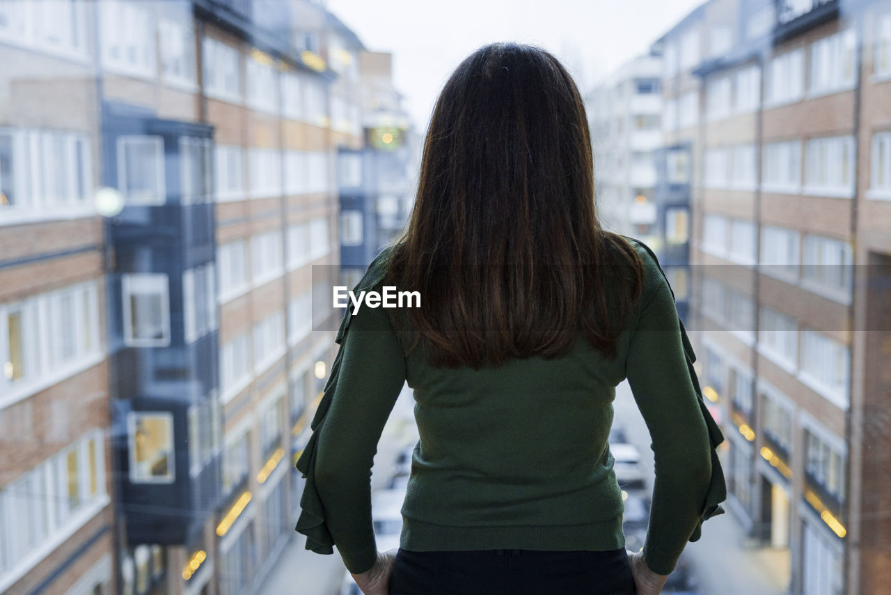 Woman looking through window at residential buildings