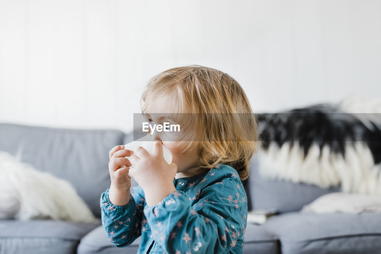 Cute girl looking away in living room at home