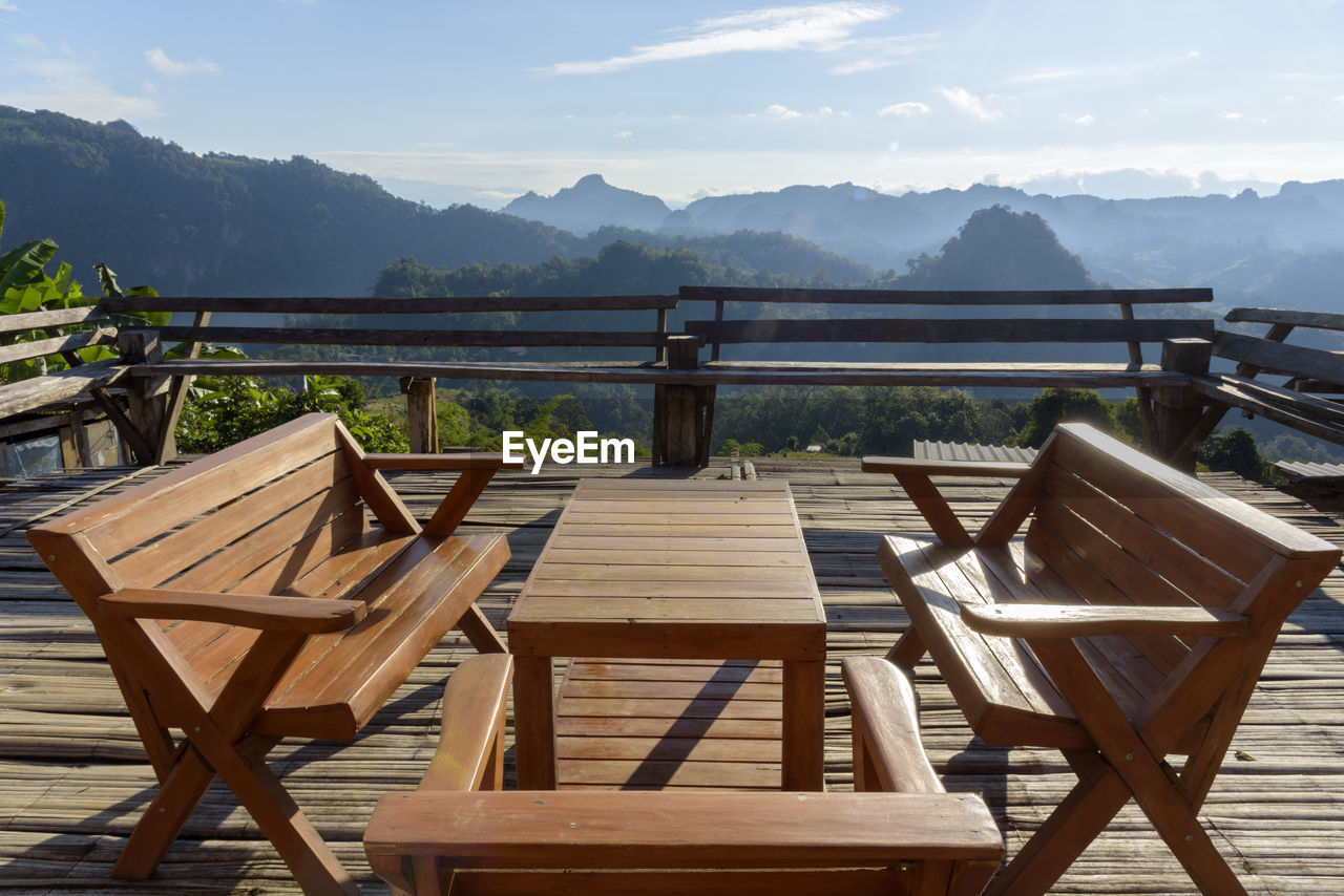 Empty chairs and tables arranged on mountain against sky