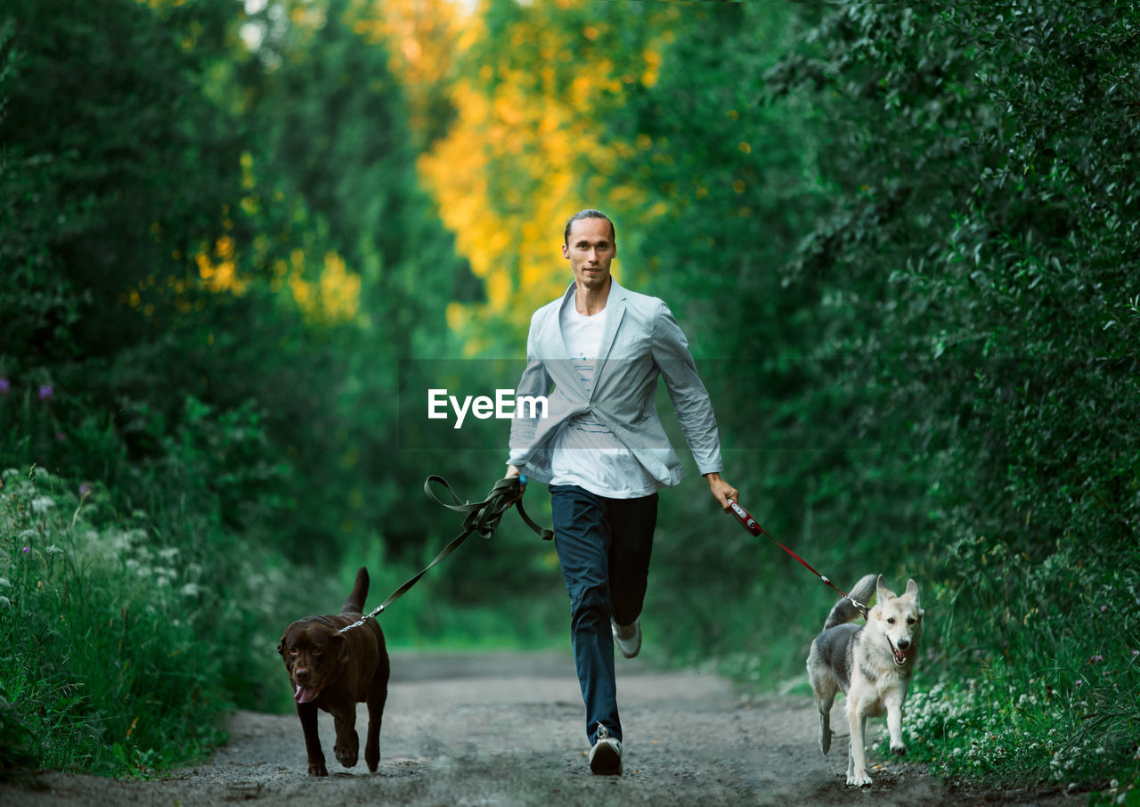 FULL LENGTH OF MAN WITH DOG STANDING AGAINST TREES