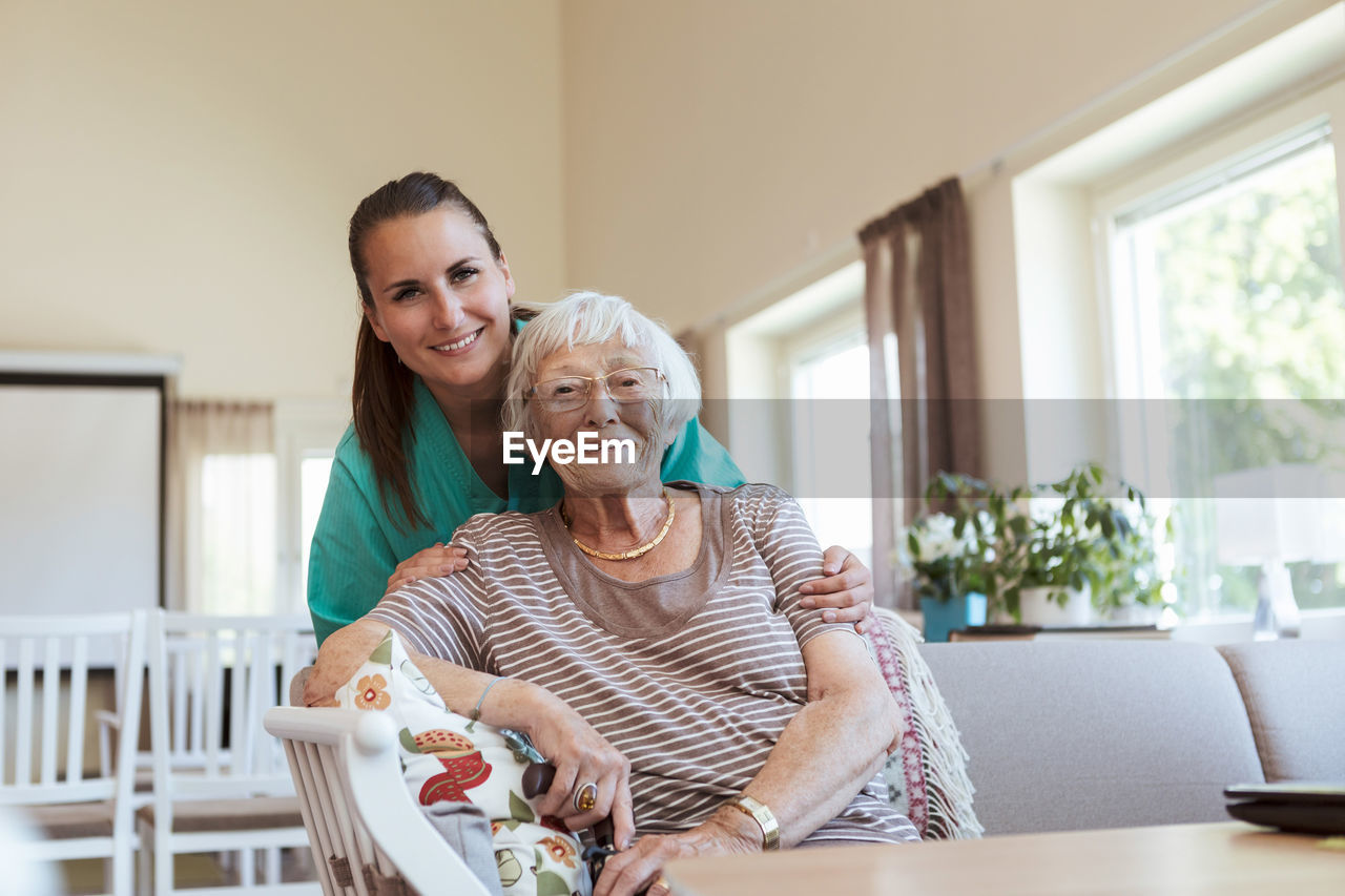 Portrait of smiling senior woman and healthcare worker at nursing home