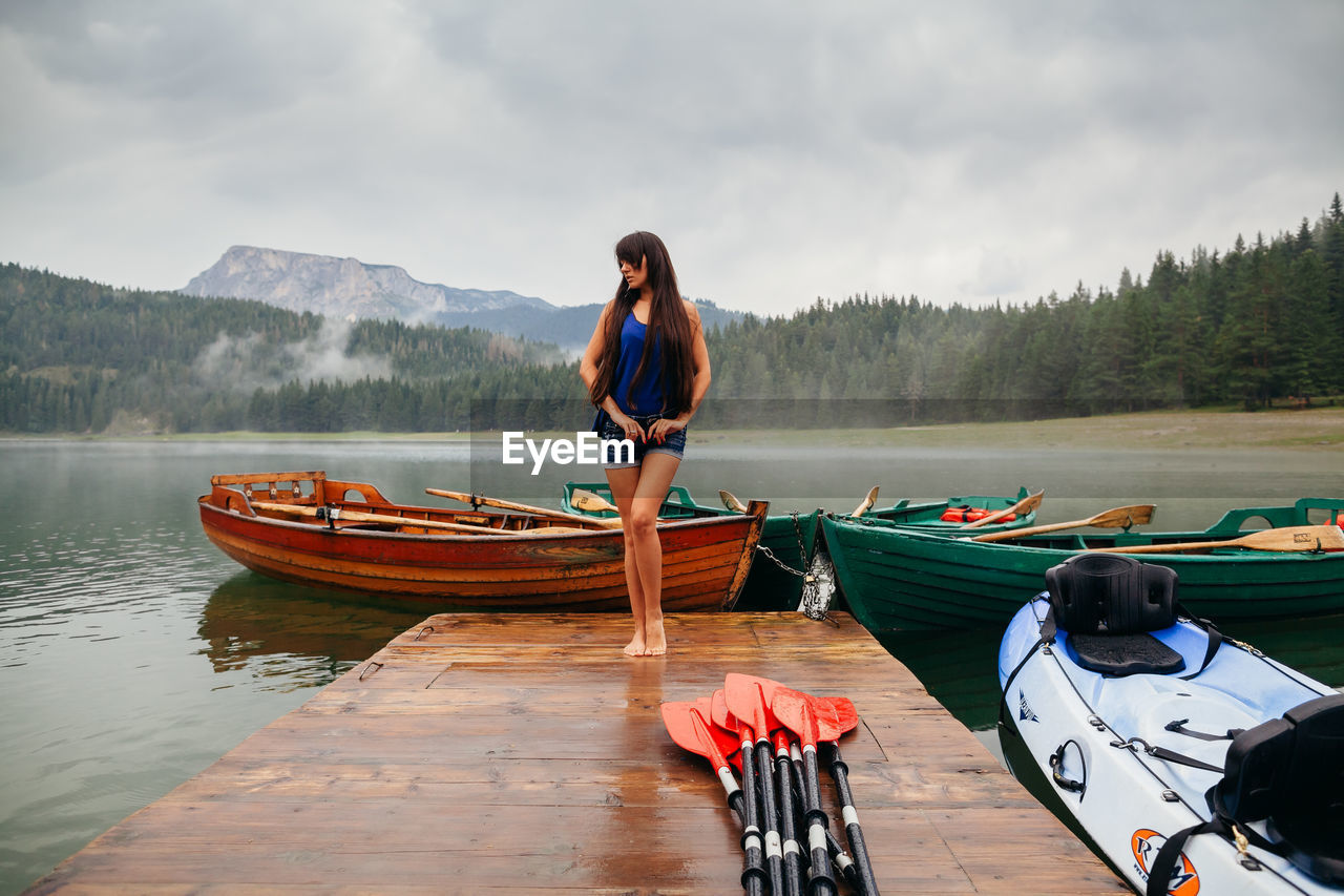 Full length of woman standing on jetty over lake