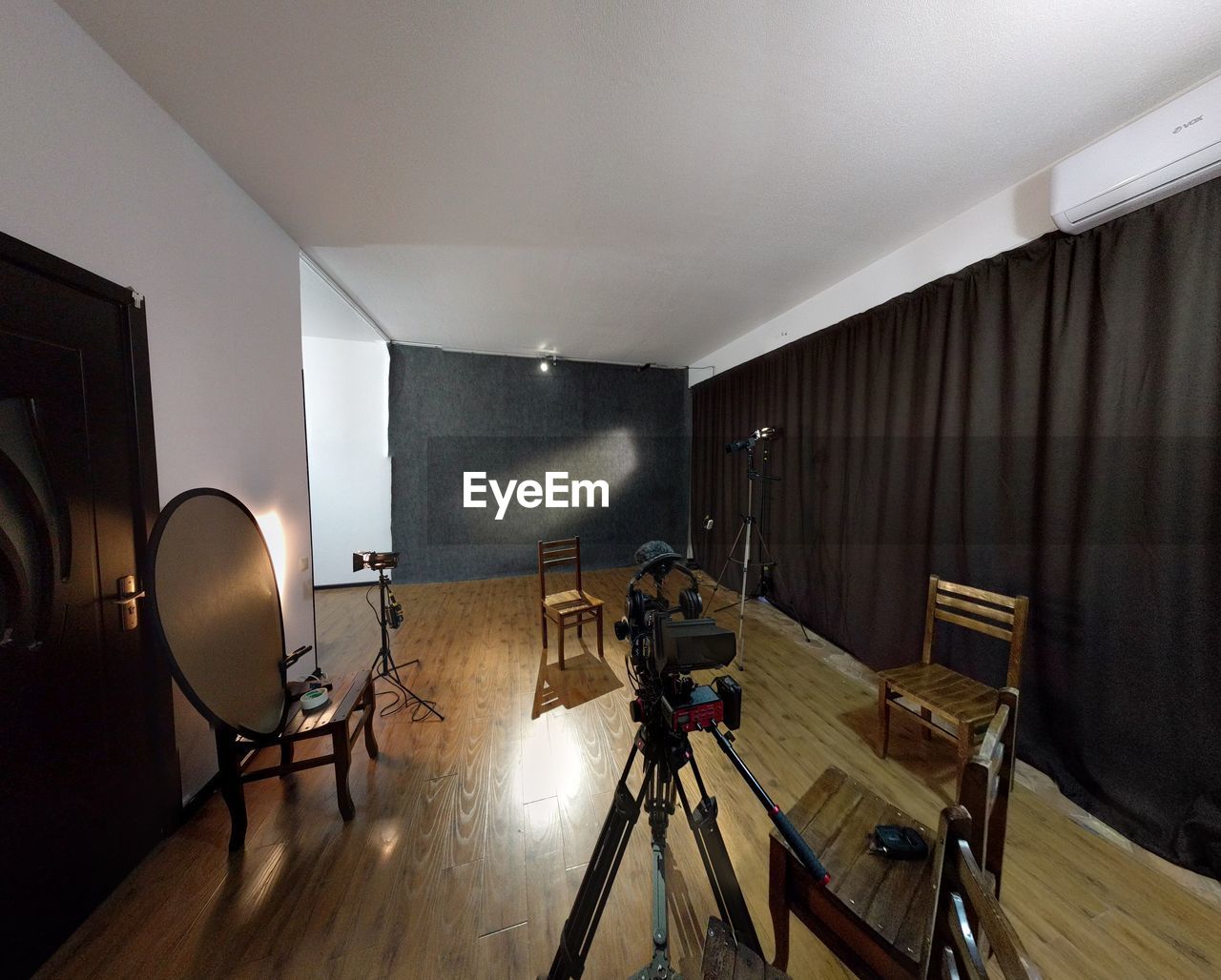 EMPTY CHAIRS AND TABLES ON HARDWOOD FLOOR IN ILLUMINATED OFFICE