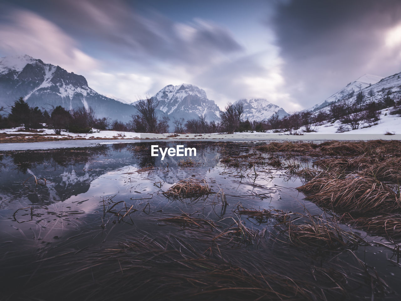 Scenic view of lake by snowcapped mountains against sky