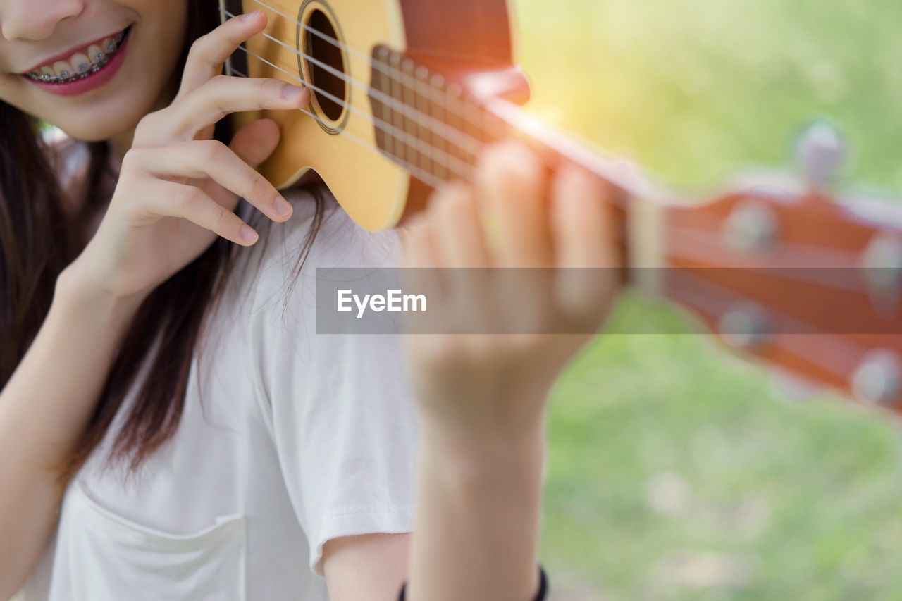 Midsection of woman playing ukulele on grass