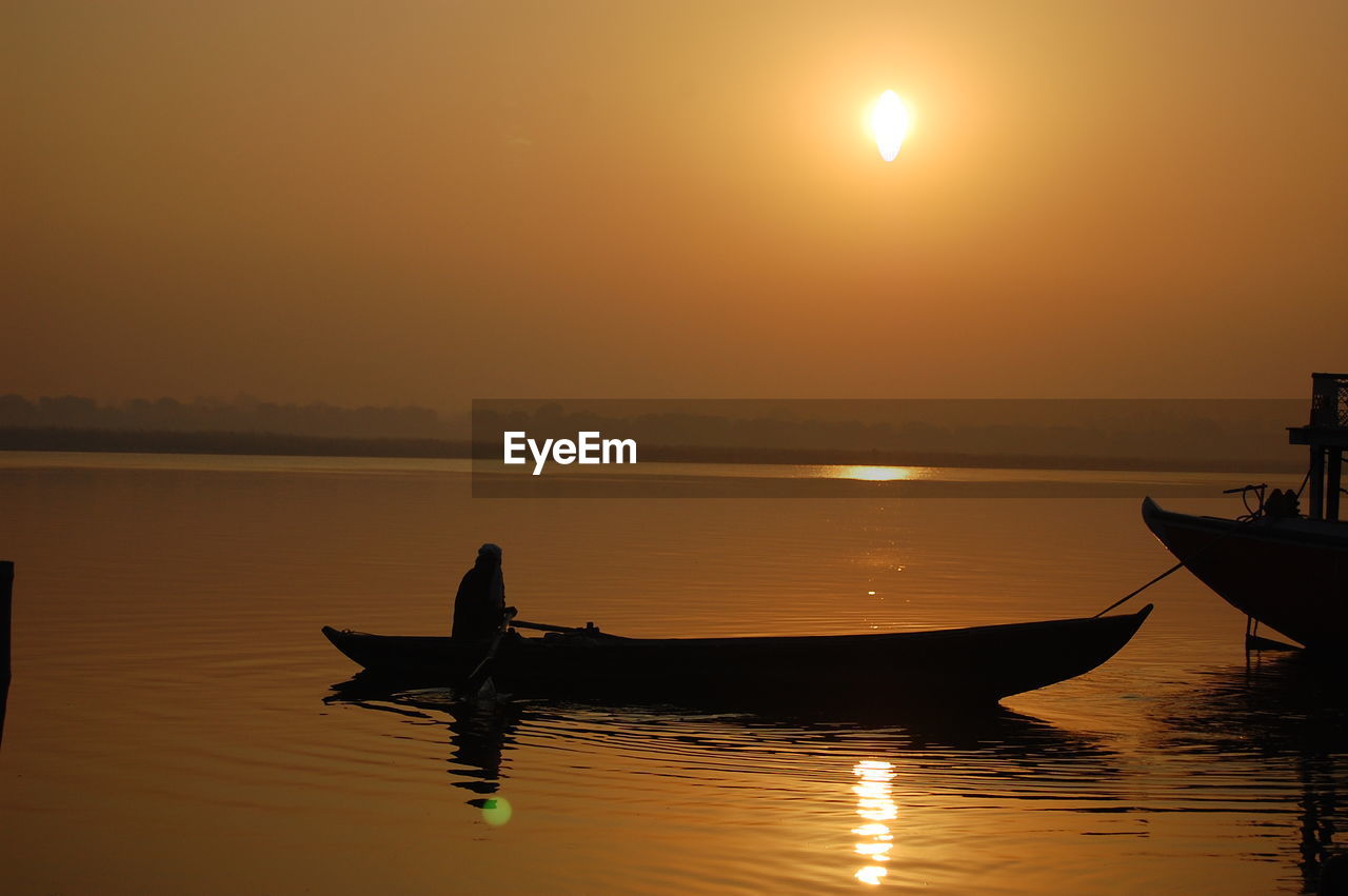 Silhouette boat moored on sea against sky during sunset