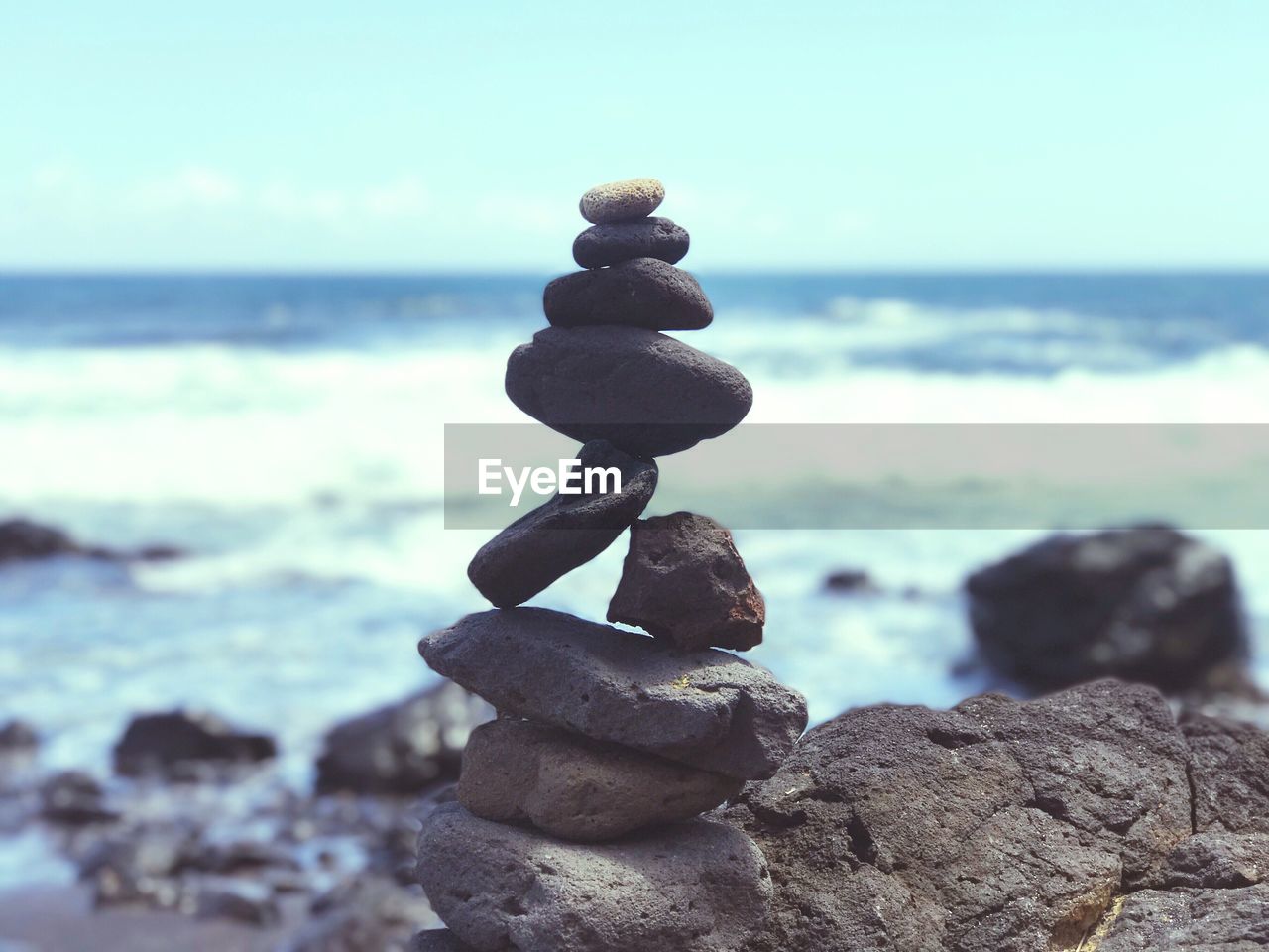 Stack of pebbles on beach against sky