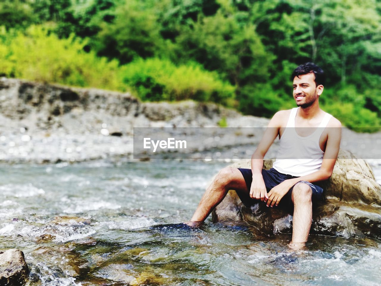 Man sitting on rock in river