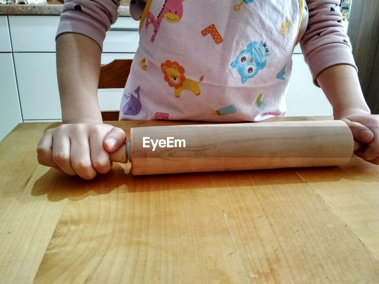 Midsection of woman holding rolling pin at table in kitchen