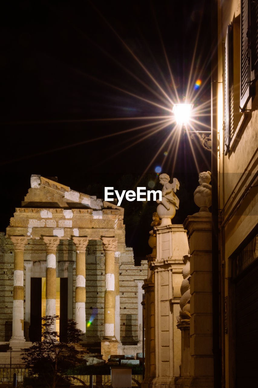 LOW ANGLE VIEW OF ILLUMINATED BUILDING AT NIGHT