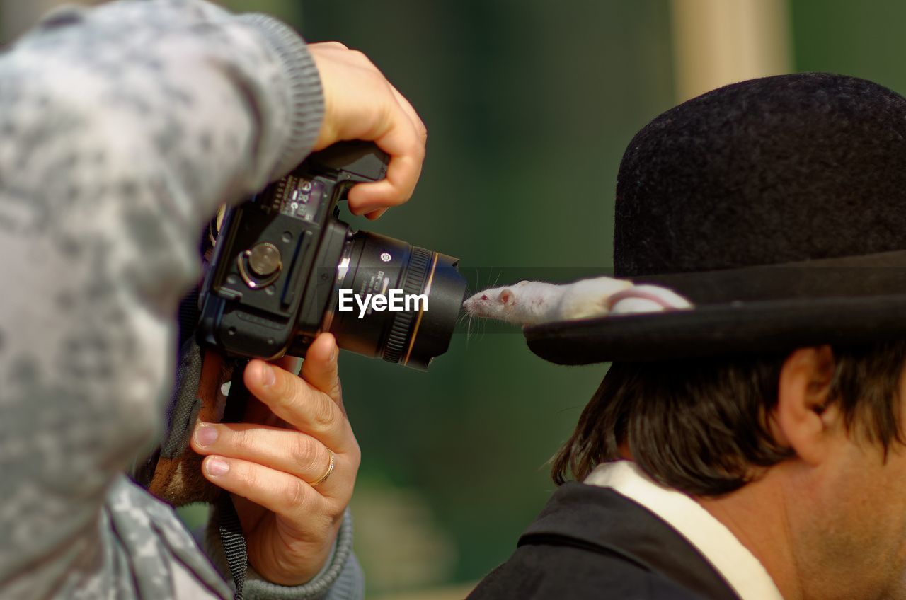 Photographer photographing rat on cap worn by man