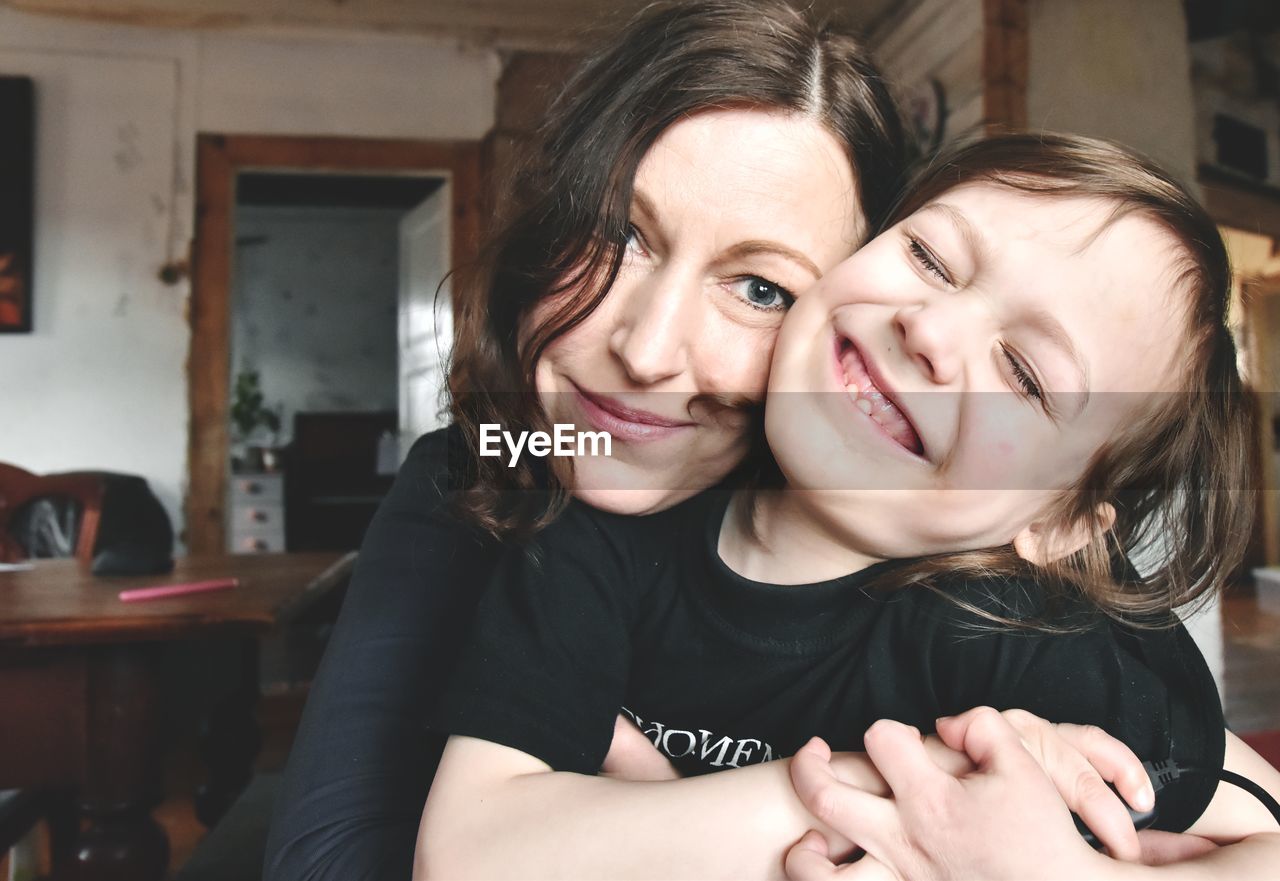 Portrait of happy mother embracing daughter at home