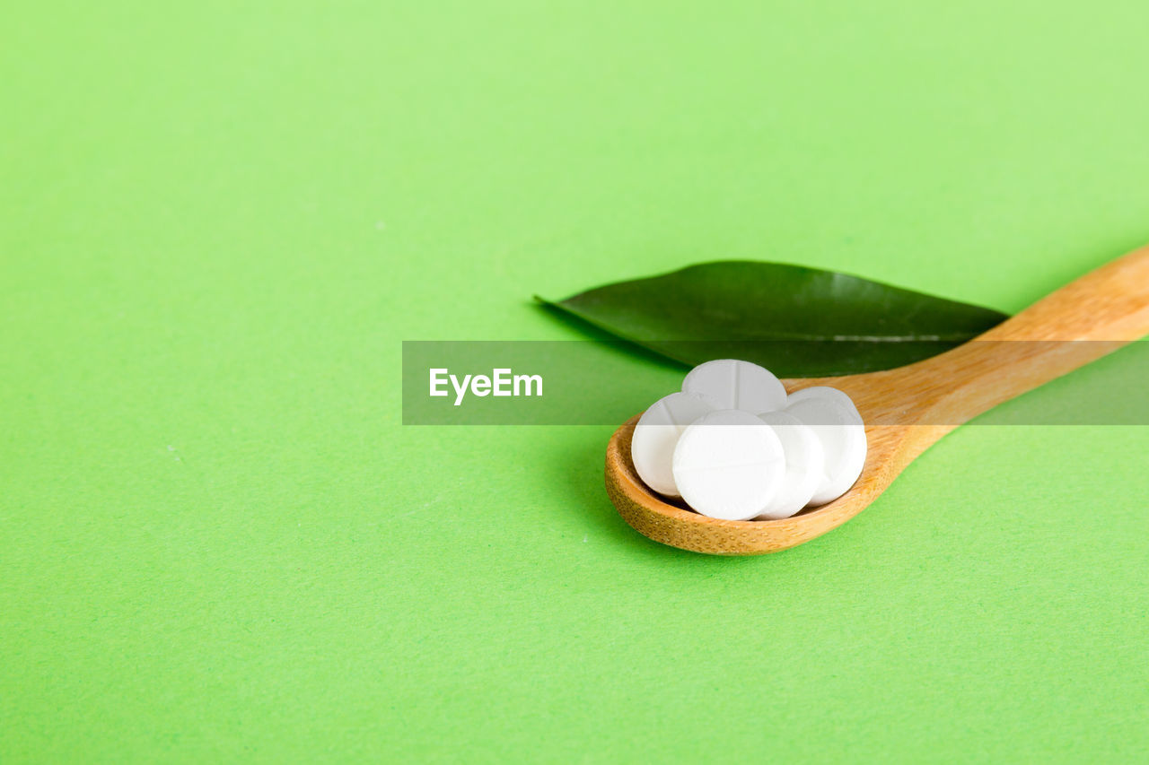 green, spoon, colored background, studio shot, copy space, no people, indoors, green background, kitchen utensil, leaf, food and drink, eating utensil, food, close-up, still life, medicine, wellbeing