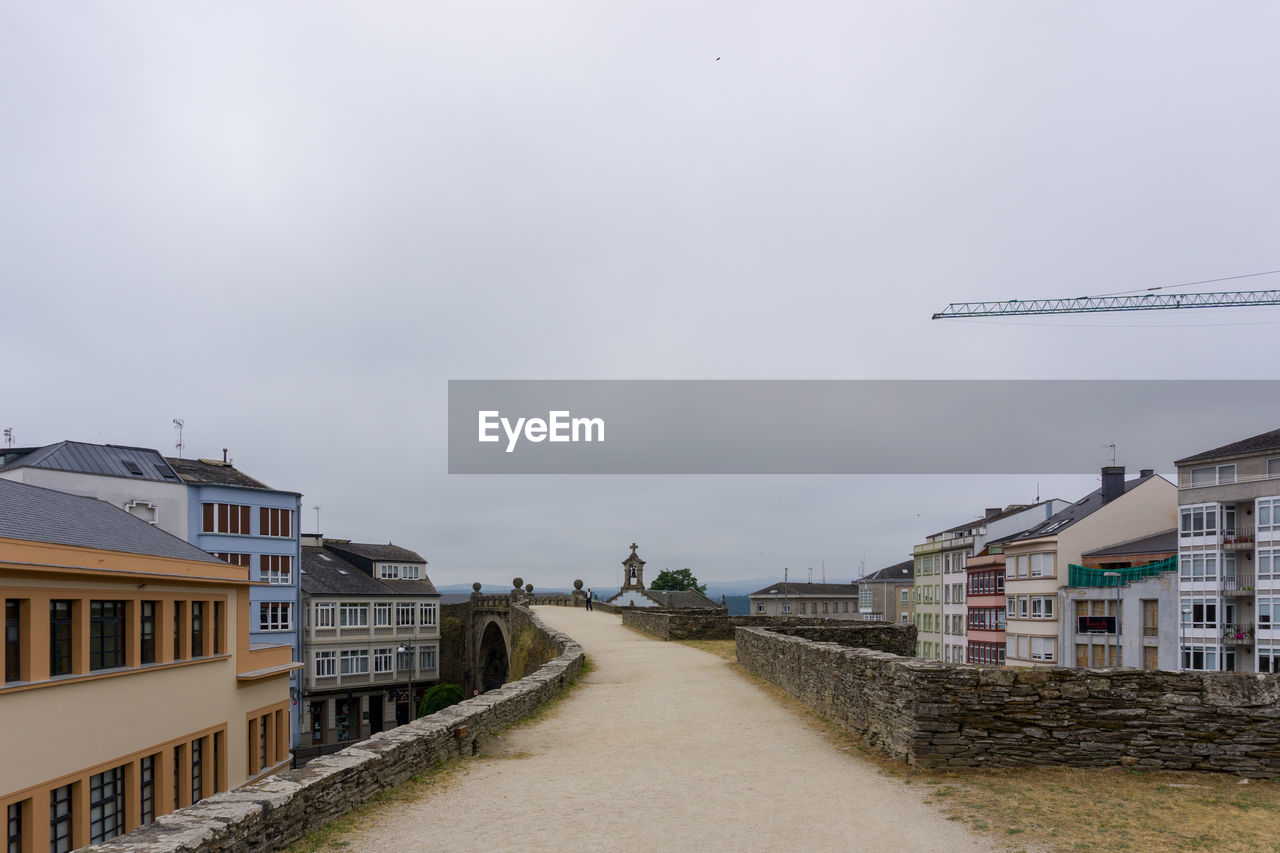 Street amidst buildings against sky in the roman wall of lugo