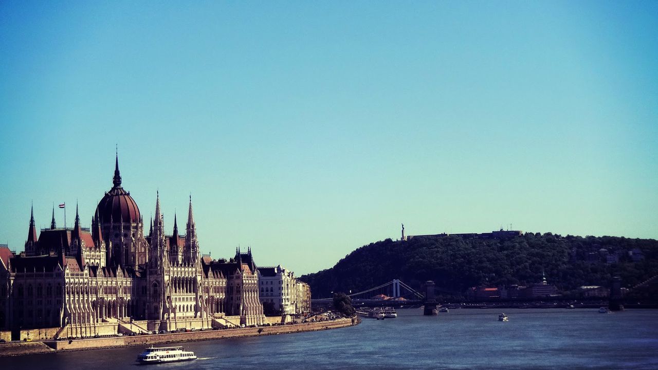 Hungarian parliament building and danube river against clear blue sky