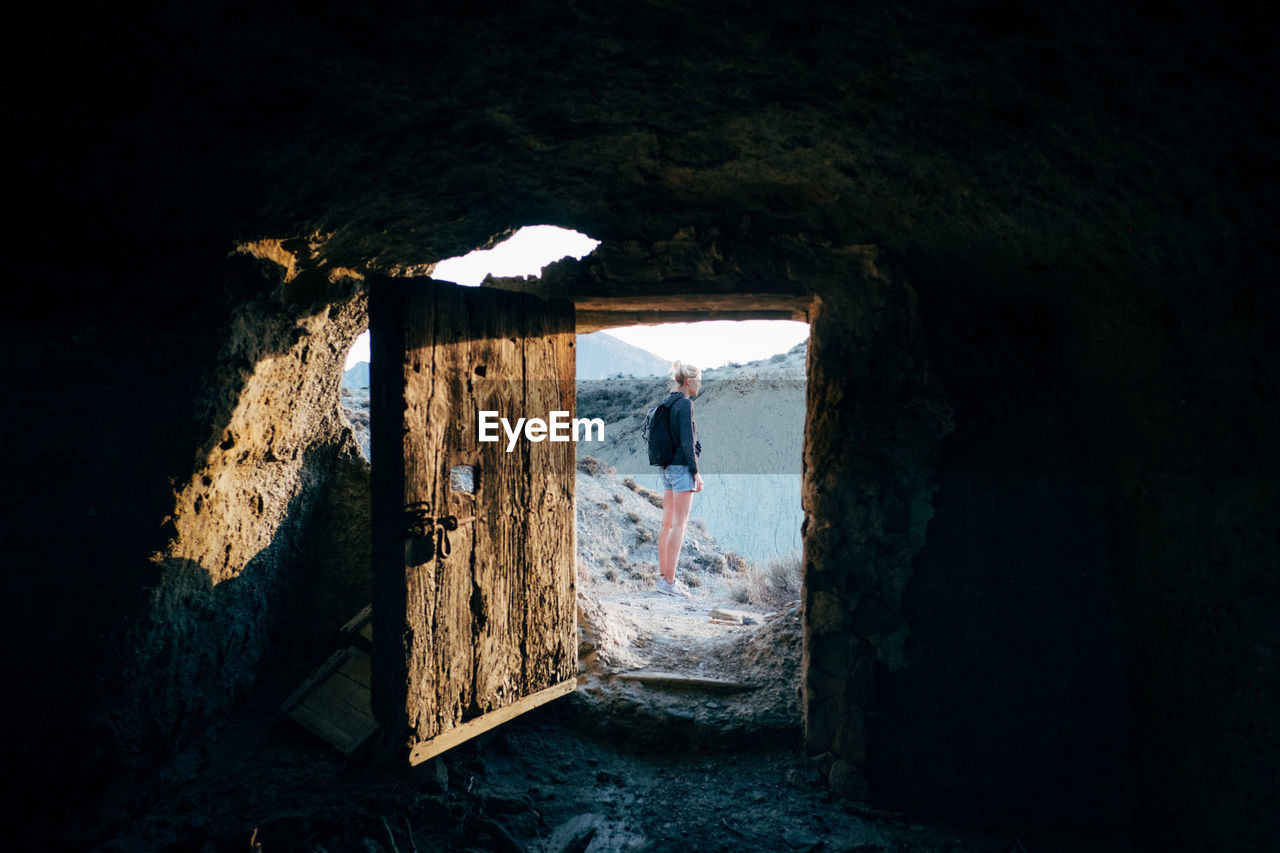 Woman standing on mountain seen through doorway