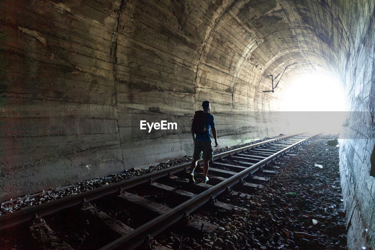 rear view of man walking on railroad station