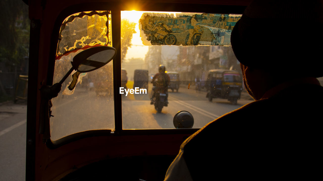 Man driving rickshaw in city during sunset