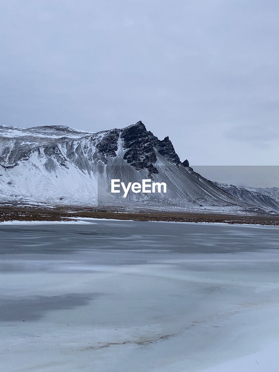 Scenic view of frozen lake by snowcapped mountain against sky