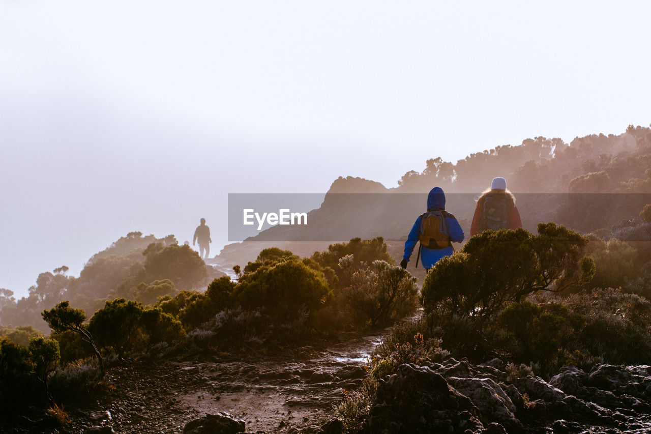 Rear view of people on rock against sky