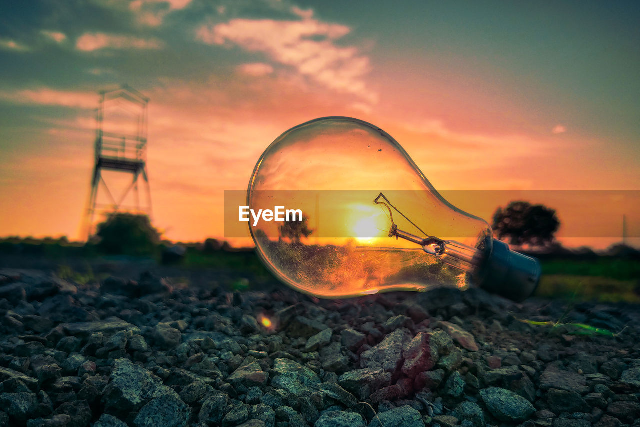 CLOSE-UP OF ILLUMINATED LIGHT BULB ON ROCK