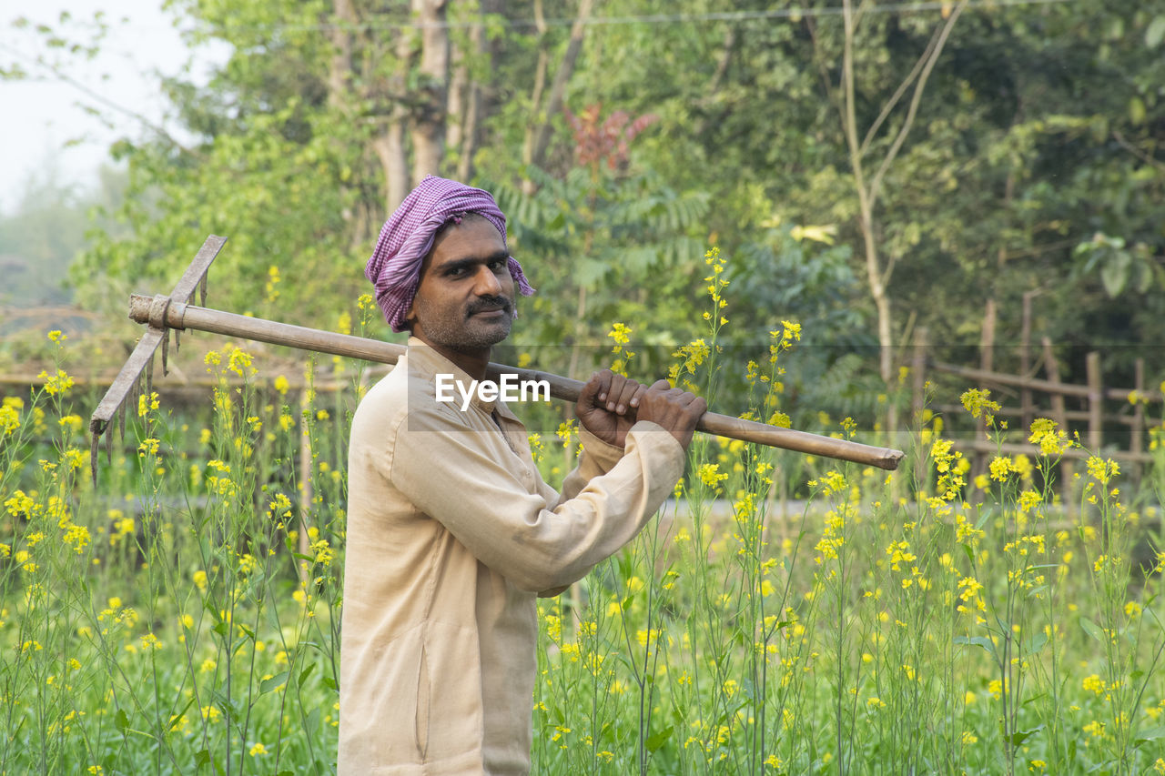 Farmer holding spade on his shoulder at farm land