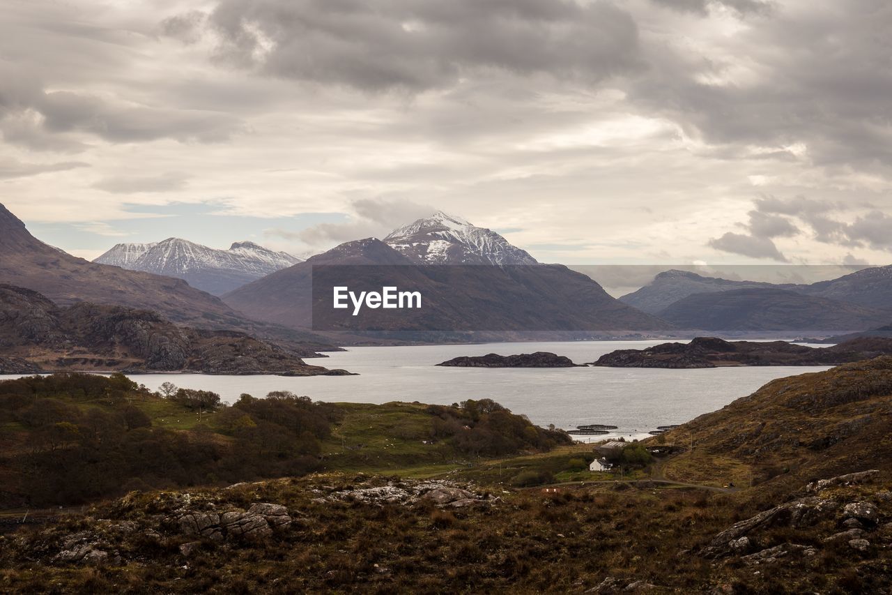 Scenic view of lake and mountains against cloudy sky