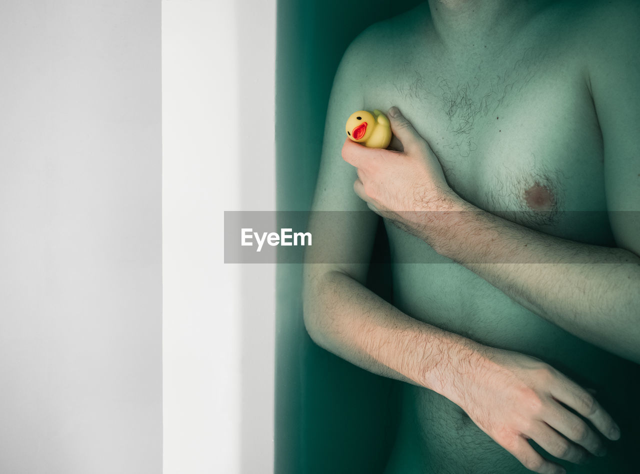 Midsection of shirtless man in bathtub