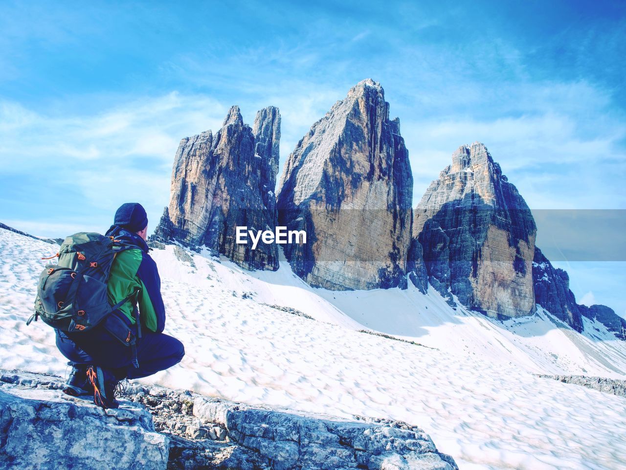 Man hiker with backpack. tre cime di lavaredo tour.  surroundings at spring time, dolomites in italy