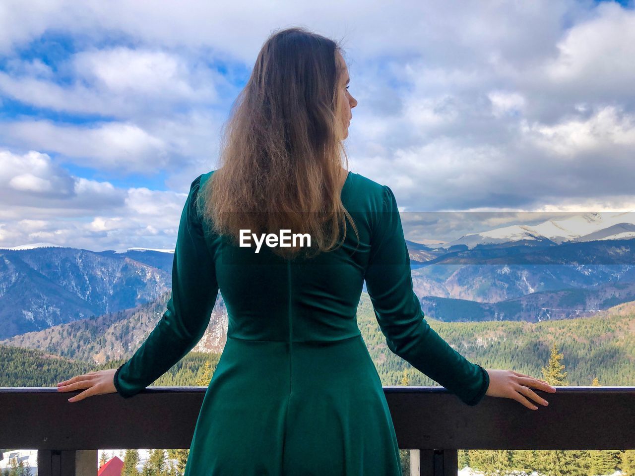 Rear view of woman standing in balcony against mountains