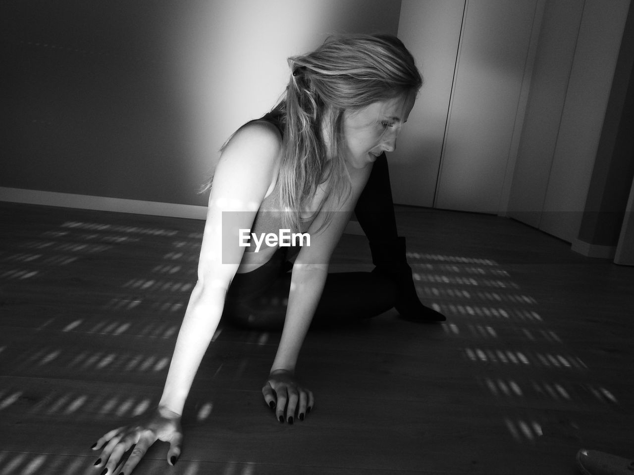 SIDE VIEW OF YOUNG WOMAN SITTING ON FLOOR IN ROOM