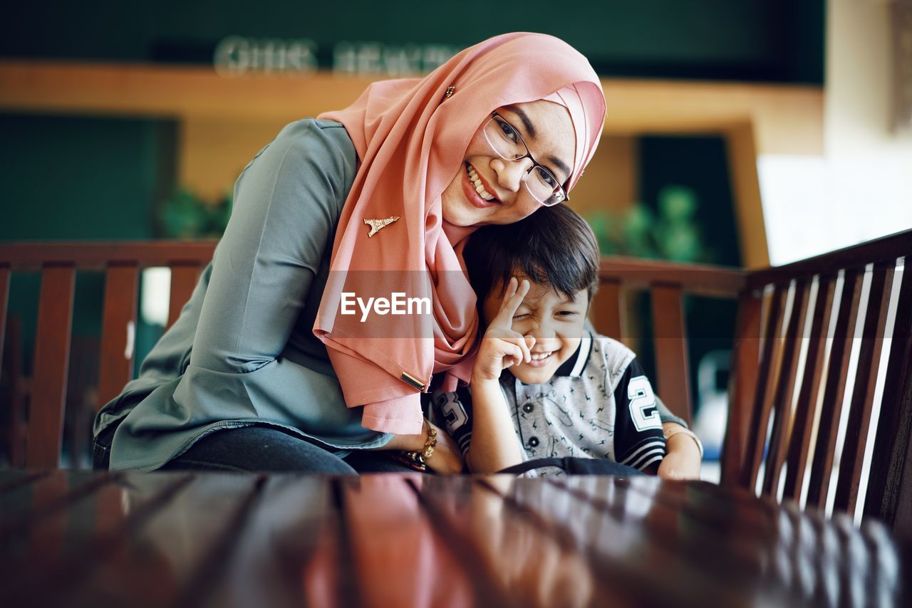 Portrait of mother smiling while sitting with son at table