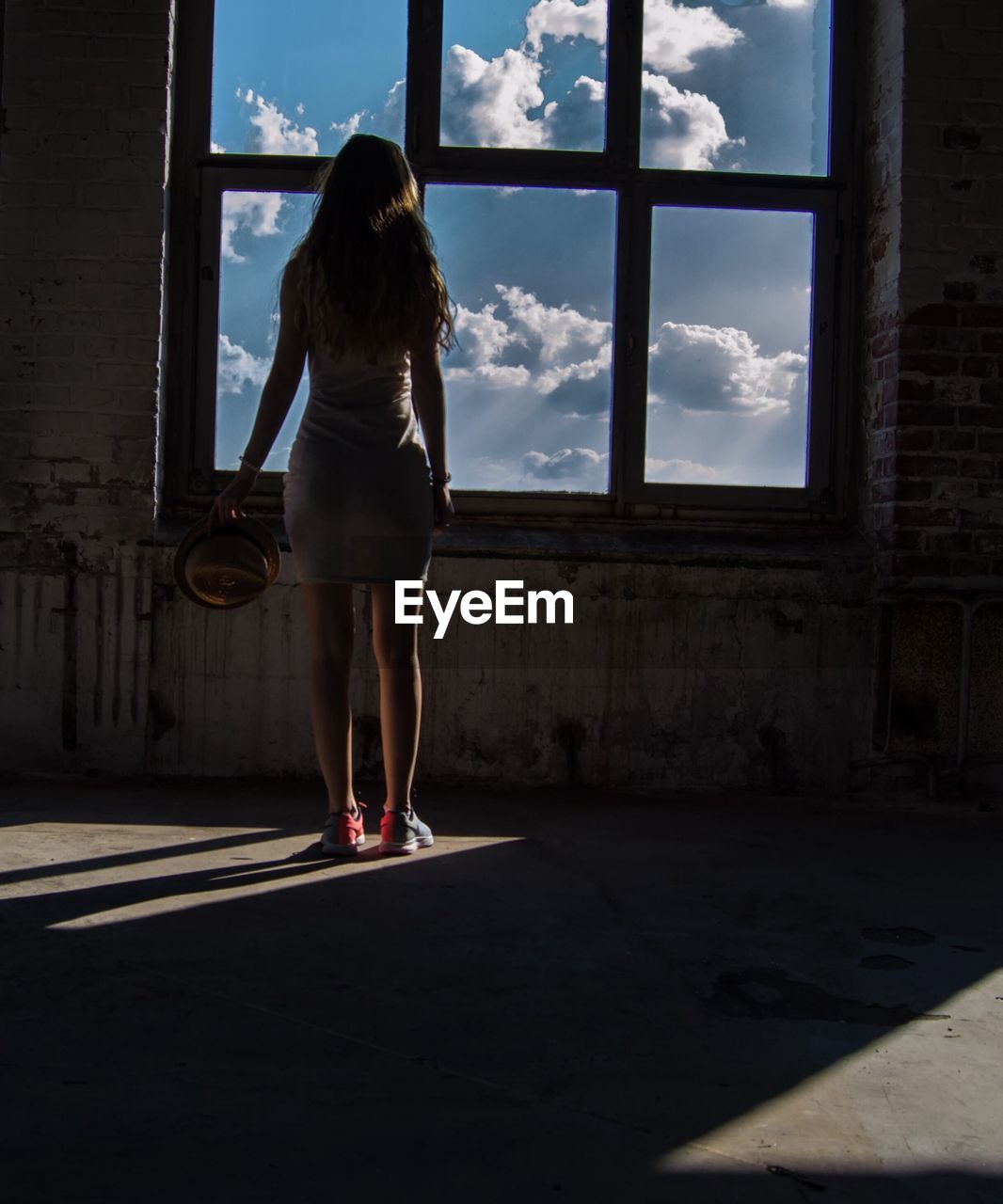 Rear view of young woman standing against window