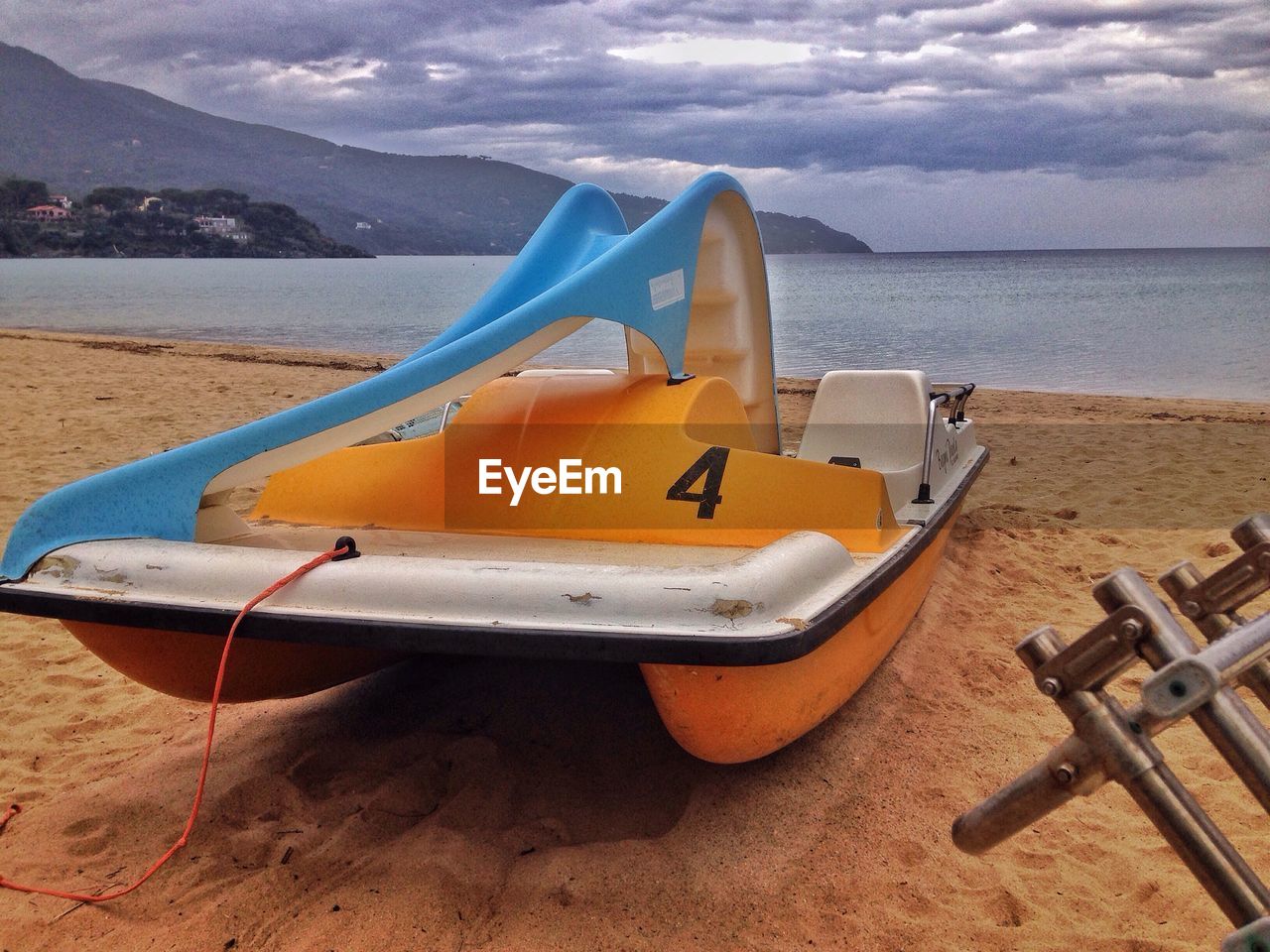 Close-up of boat moored on beach against sky