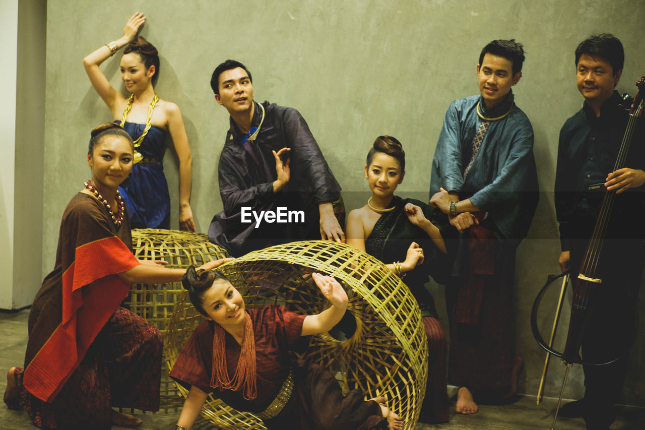 Models wearing traditional clothing while posing against wall