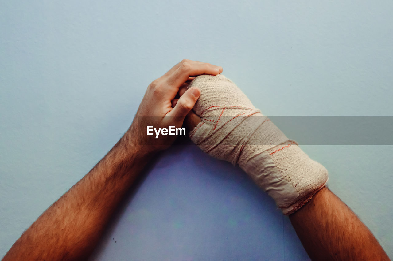 Cropped hand of man wrapped in bandage on table