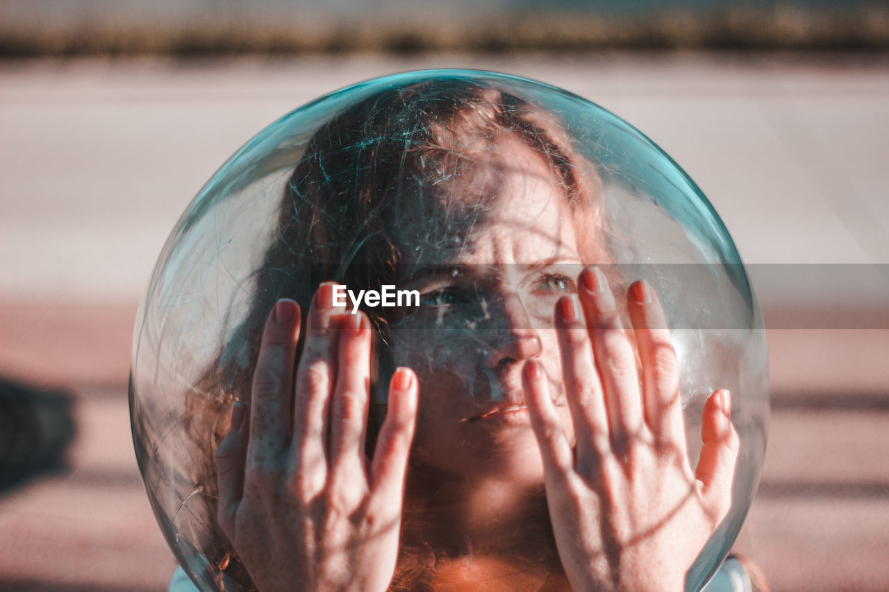 Close-up of thoughtful young woman wearing glass helmet in head during sunny day