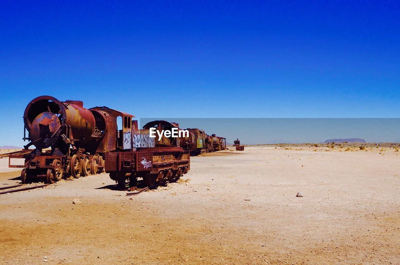 Abandoned train on desert against clear sky