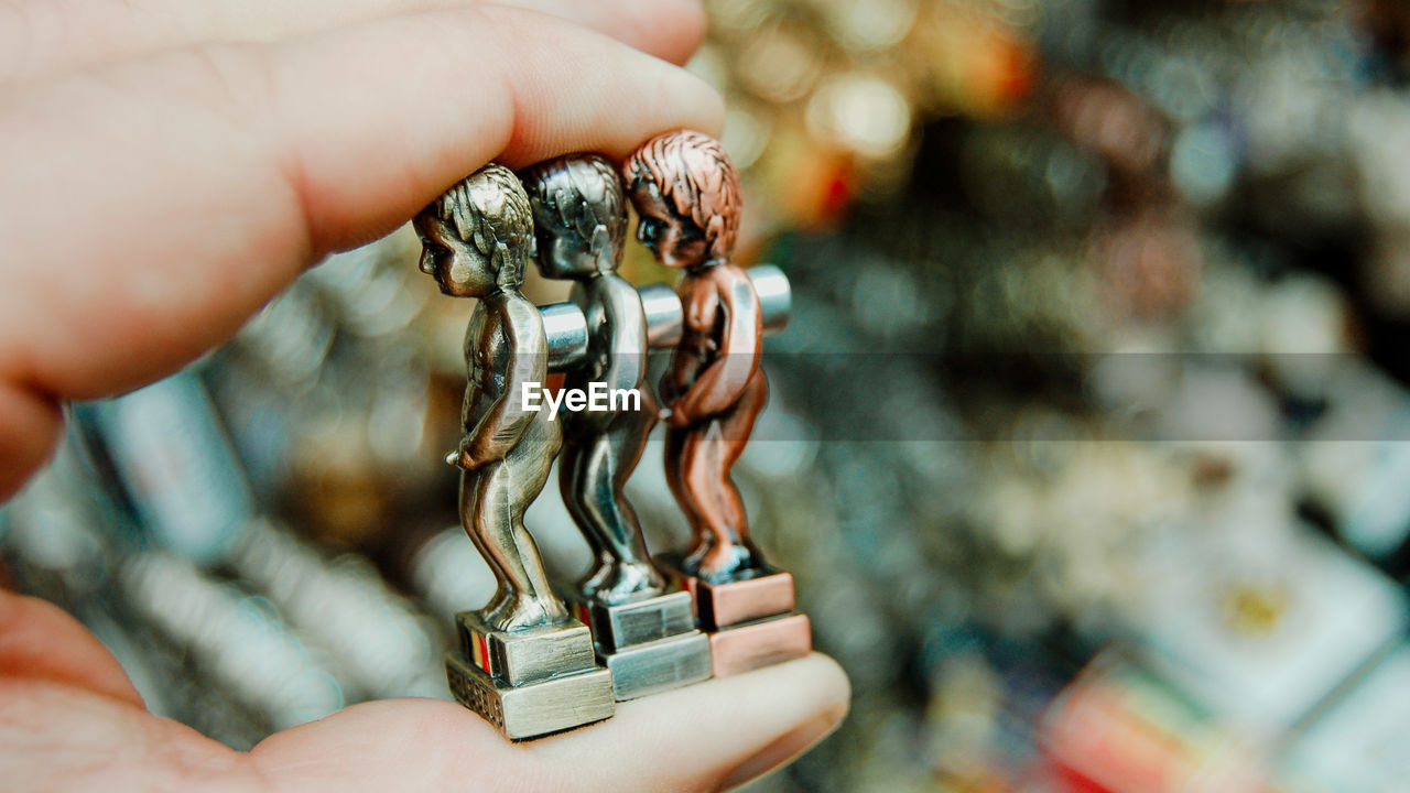 Close-up of human hand holding metallic figurines