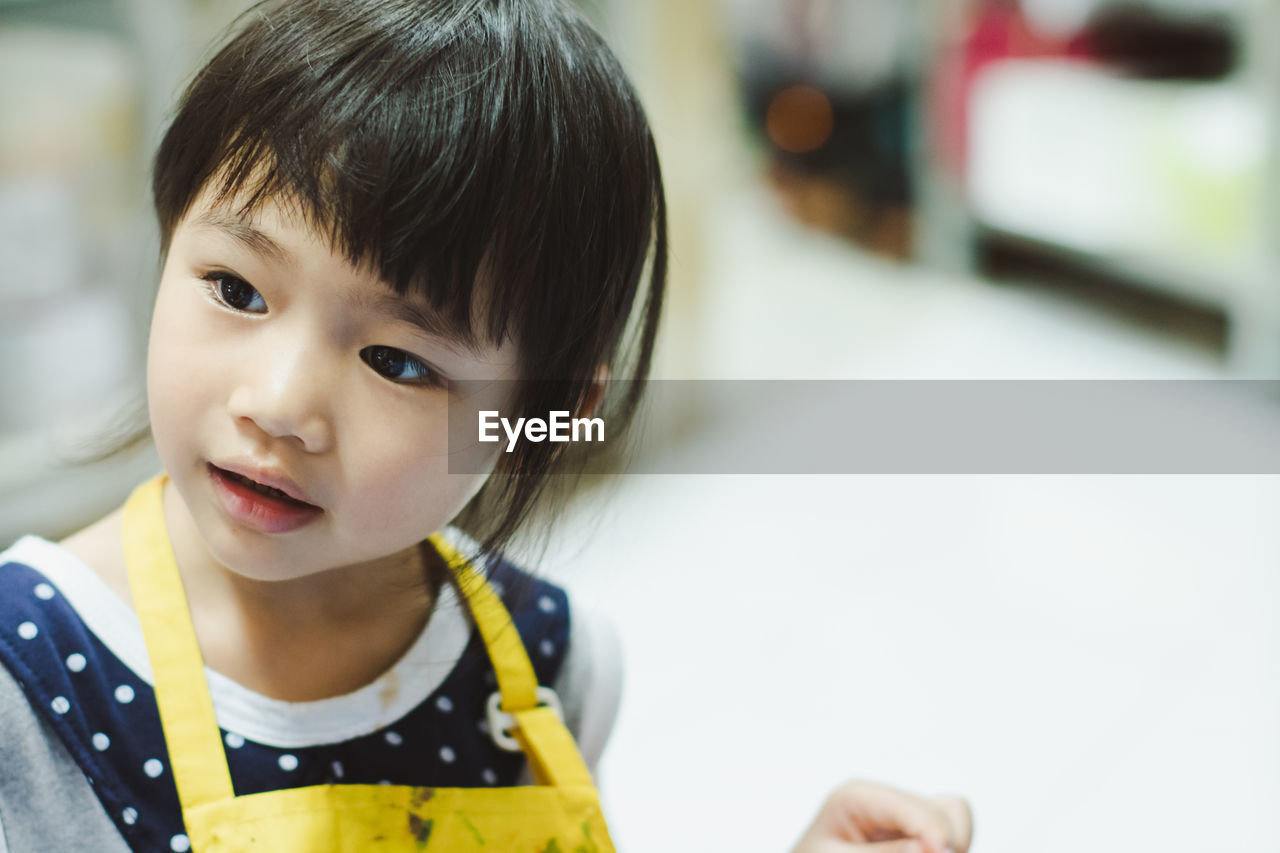 Close-up of cute girl looking away at home