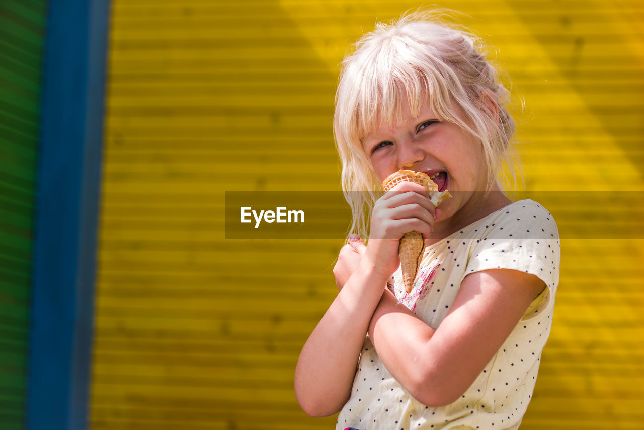 Portrait of girl eating ice cream cone while standing outdoors