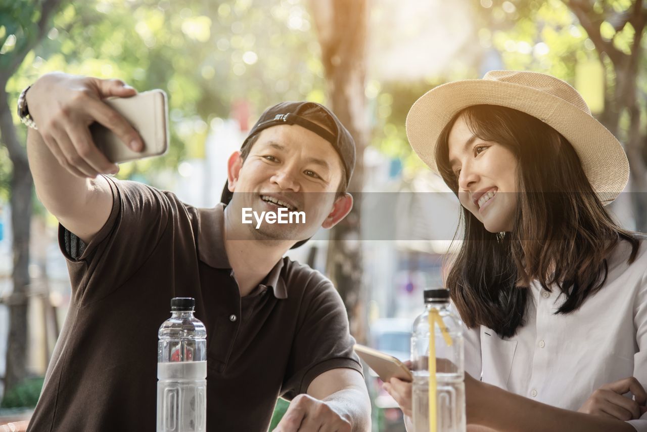 Smiling man taking selfie with girlfriend on smart phone at table