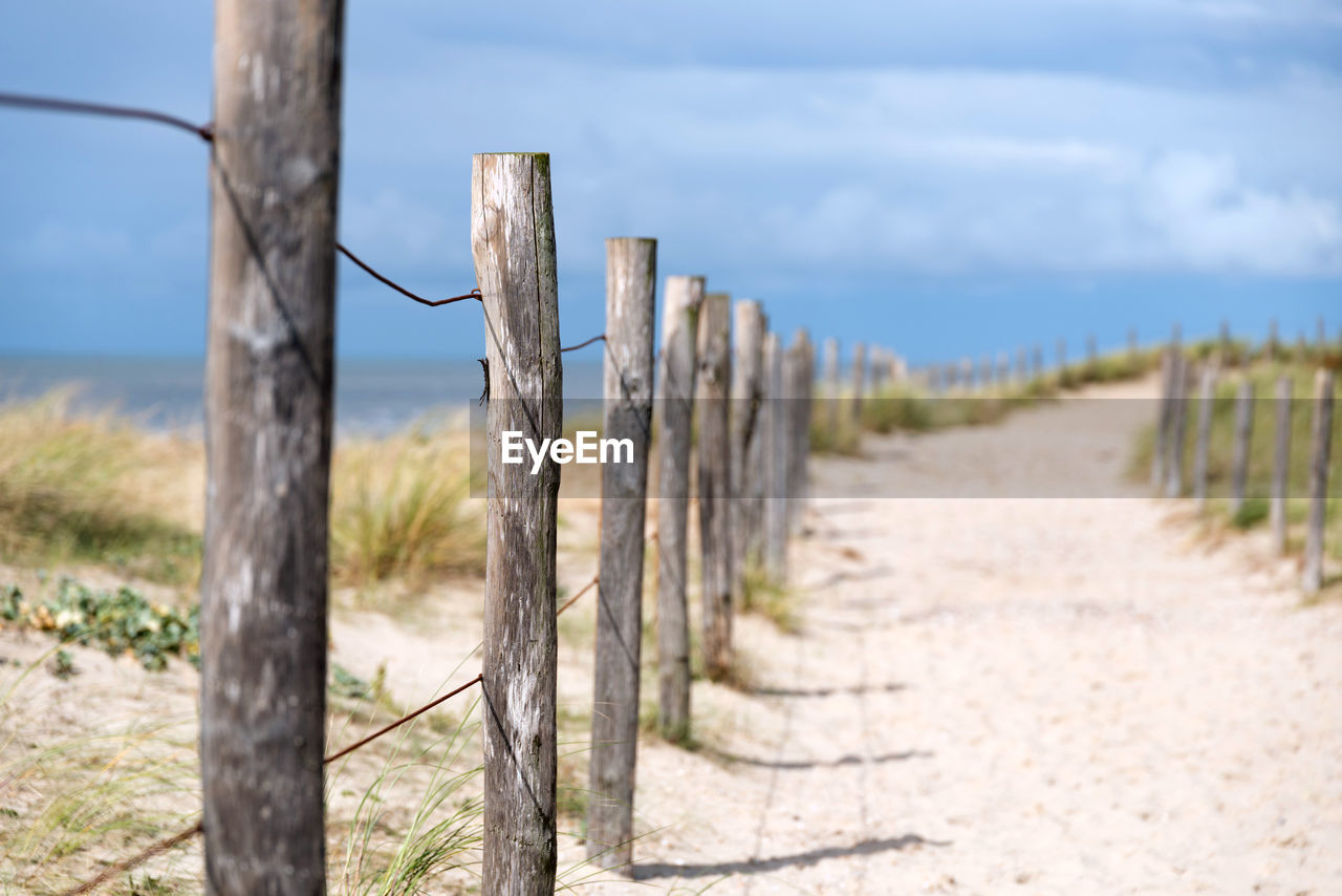 CLOSE-UP OF WOODEN POST ON FIELD AGAINST SKY