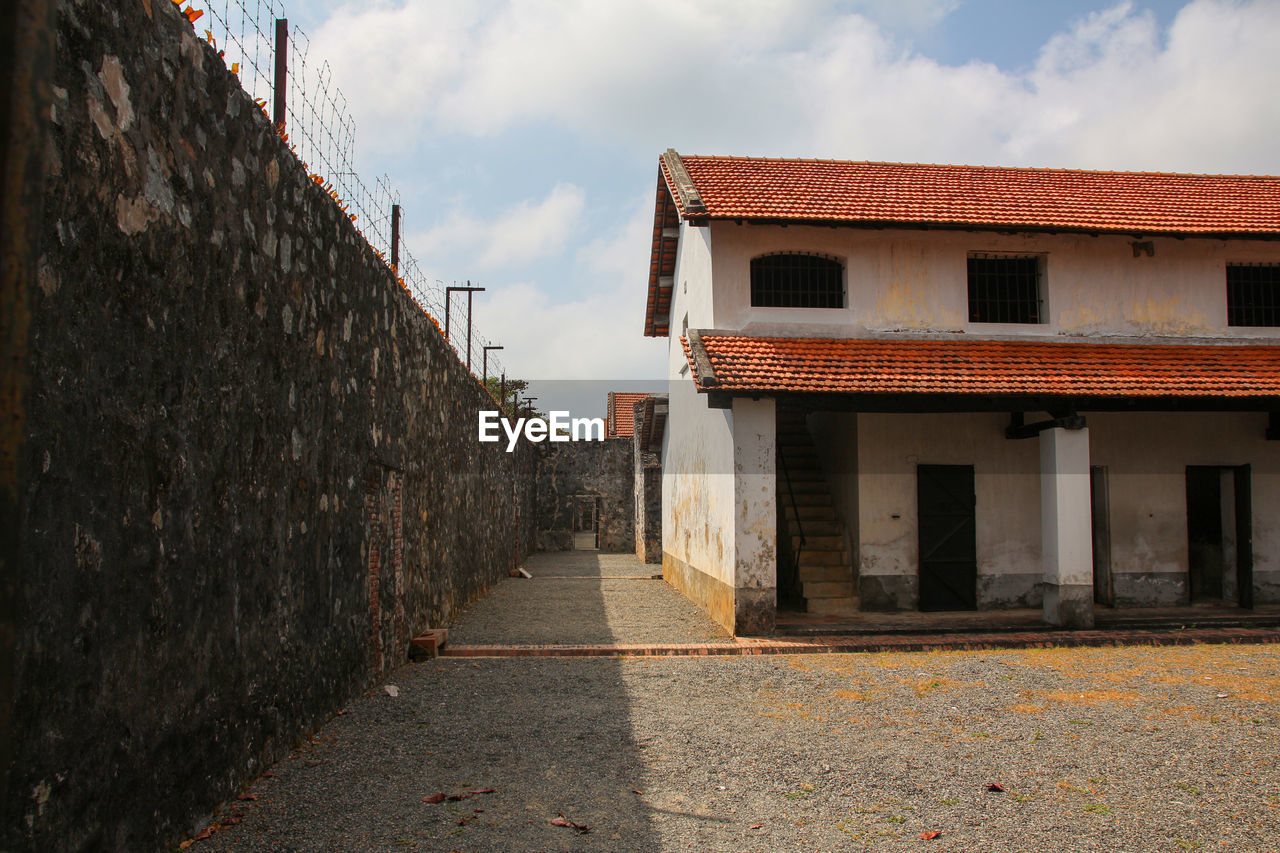 FOOTPATH AMIDST HOUSES AGAINST SKY