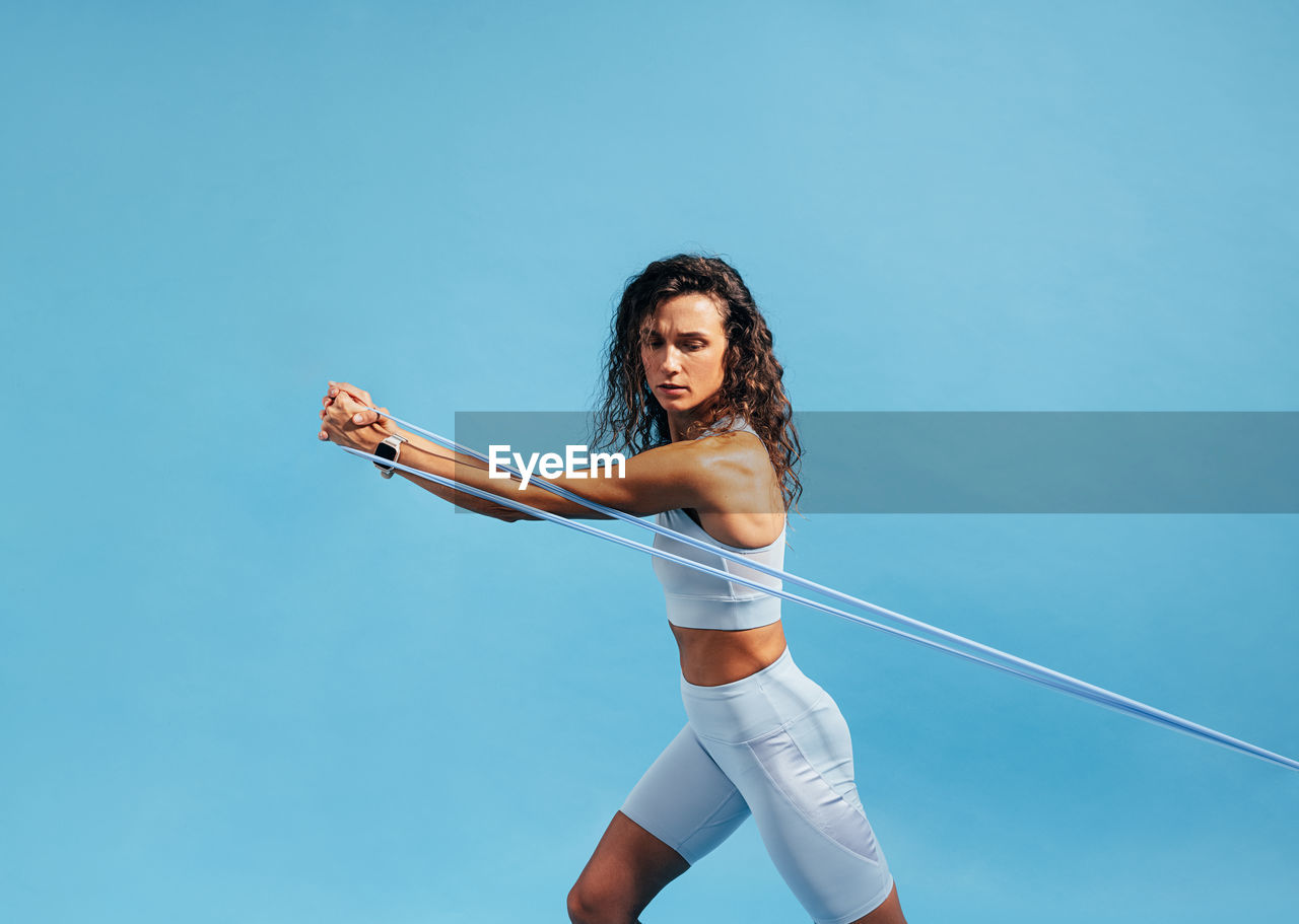 Woman exercising against blue background